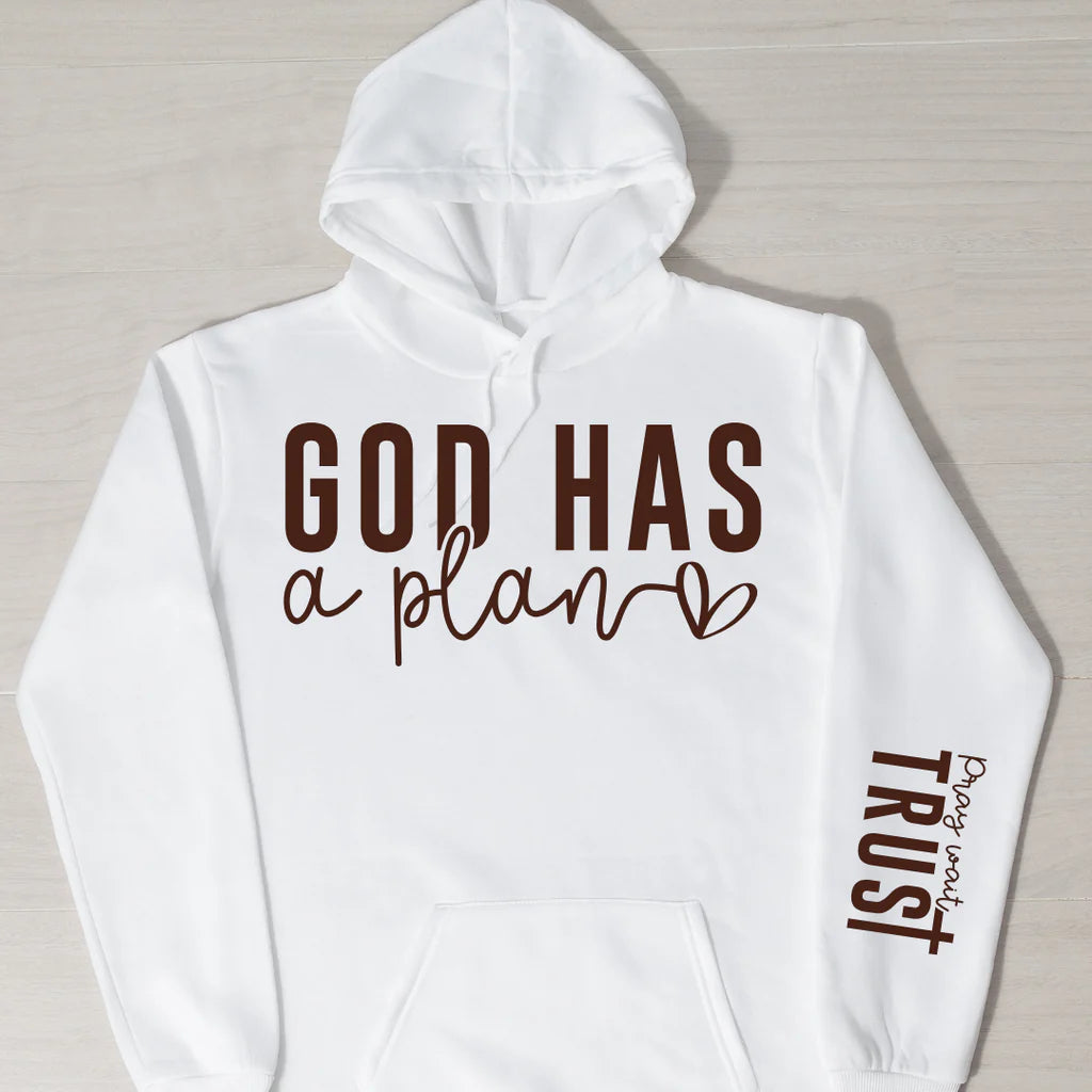 White cotton blend hoodie with the phrase "God Has a Plan" in bold brown lettering on the chest and "Pray, Wait, Trust" on the sleeve, displayed against a light neutral background.